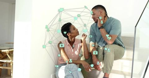 Couple sitting on stairs talking with digital teal network overlay representing connection