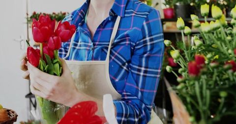 Florist arranging red tulips in vase inside flower shop