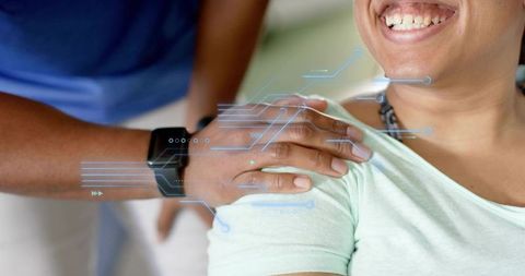 Smiling patient receiving supportive shoulder touch while caregiver wearing smartwatch hud