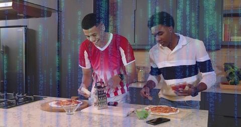 Young men grating and topping homemade pizzas on kitchen counter with digital code overlay