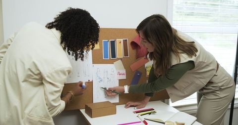 Diverse female designers collaborating on fashion sketches and color palette