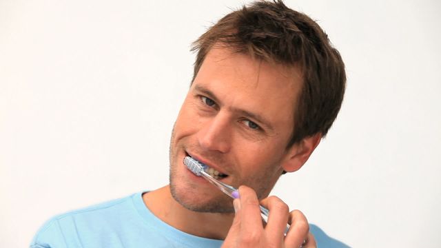 Man brushing teeth with a toothbrush, focusing on dental hygiene and oral care. Ideal for dental care advertisements, health blogs, and educational materials on daily hygiene practices.