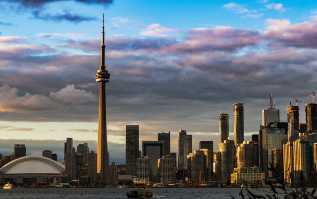Toronto's skyline at sunset features the CN Tower, skyscrapers and the waterfront, ideal for travel blogs, tourism advertisements, architectural magazines, and urban-themed presentations. Highlights the city's urban development and vibrant cultural scene.