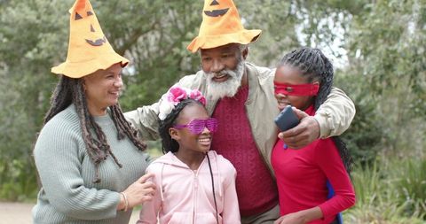 Multigenerational African American Family Wearing Pumpkin Hats Taking Selfie in Park