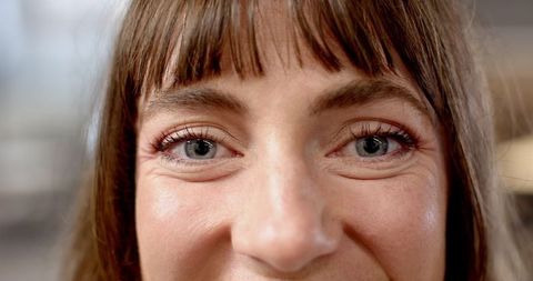 Close-Up of Woman Applying Mascara and Reddish Eyeshadow Indoors