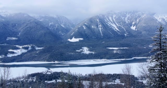A serene winter landscape showcases a frozen lake surrounded by snow-covered mountains, with a hint of a small community nestled at the foothills. The tranquility and beauty of the scene suggest a perfect destination for those seeking a peaceful retreat in nature.