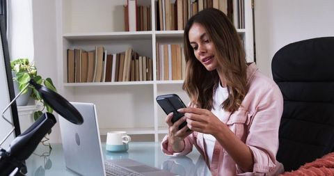Woman Engaged in Office Work with Laptop and Smartphone