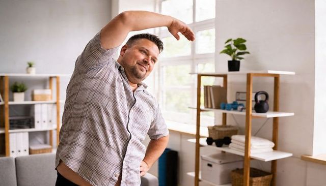 Man stretching in sunlit living room practicing gentle mobility, flexibility and balance
