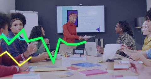 Presenter handing documents during team meeting with neon data graph overlay