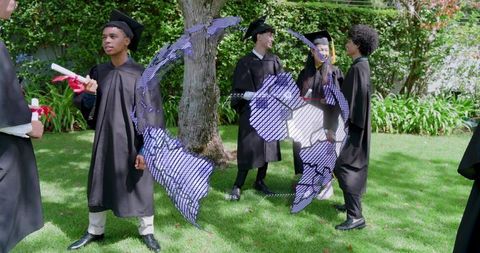 Multicultural graduates celebrating outdoors in caps and gowns holding diploma scrolls