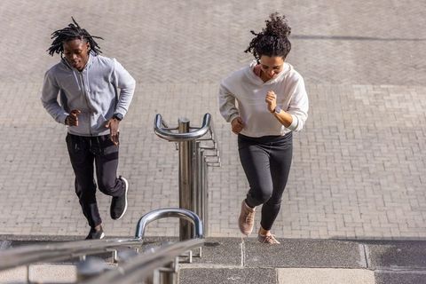 Young african american friends running up urban staircase during outdoor workout