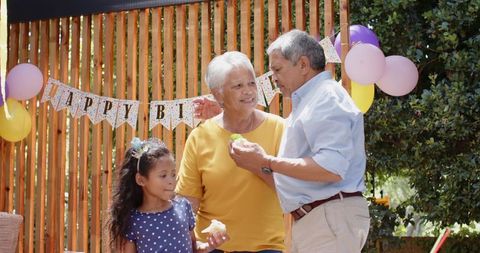 Grandparents Celebrating Backyard Birthday, Granddaughter Holding Cupcake, Feeding Moment