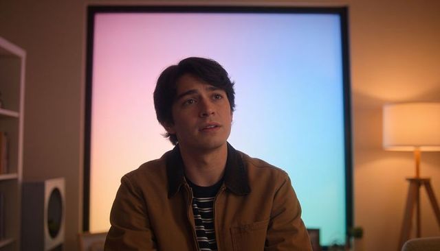 Young man sitting in cozy home studio with pastel led gradient panel and ambient lighting