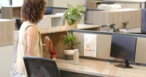 Woman entering office arranging reusable water bottle and plant at modern workstation