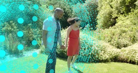 Holding hands in sunlit garden with teal digital dot overlay — romantic outdoor couple