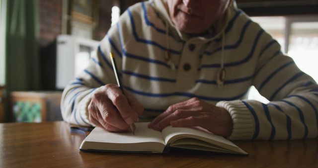 Caucasian senior man writing in notebook at home. Retirement, senior lifestyle, happiness, domestic life and wine making, unaltered.