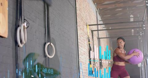 Rotating with medicine ball in industrial gym with fitness analytics overlay and gym rings