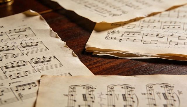 Aged sheet music and handwritten manuscripts on wooden tabletop evoking vintage melody