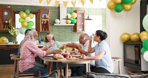 Senior Friends Enjoying Celebration with Wine at Home Dinner Gathering