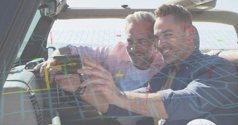 Two men smiling while using smartphone with ar navigation overlay in convertible road trip