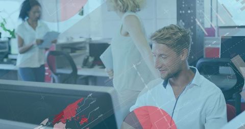 Young professional analyzing global data visualization on monitor in modern open-plan office