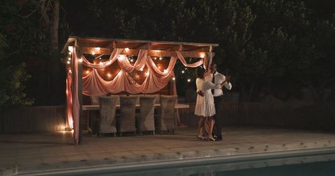 Romantic Poolside Dance Under Illuminated Gazebo at Night