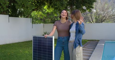 African american friends holding solar panel by pool in bright backyard moment smiling