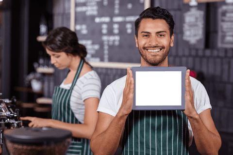 Confident man holding tablet with blank screen offers versatility for digital integration. Ideal for business advertisements, app promotion, customizable content in coffee shop environment concept. Demonstrates blend of technology access and friendly service.