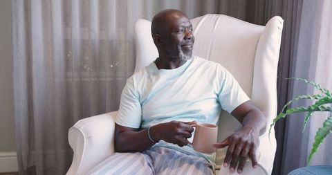 Senior Man Relaxing with Coffee by Window in Comfortable Home Interior