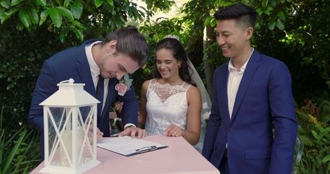 Bride and groom signing wedding certificate outdoors