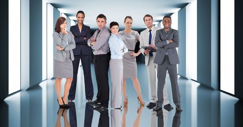 Group of business professionals confidently standing in a modern office corridor. They showcase diversity and teamwork, all dressed in professional attire. Ideal for illustrating corporate environments, advertising teamwork, or diversity in the workplace.