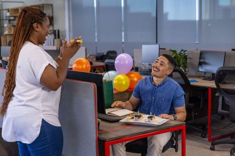 Colleagues celebrating birthday in modern office workstation