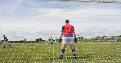 Goalkeeper practicing with team on park soccer field