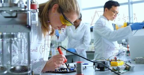 Engineer Soldering PCB Prototype in Collaborative Electronics Lab with Protective Goggles