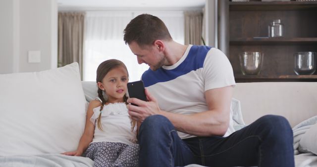 Father Showing Daughter Something on Smartphone in Living Room - Download Free Stock Images Pikwizard.com