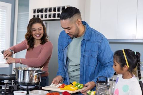 Family cooking together in modern kitchen parents and daughter preparing healthy meal