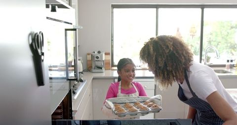 Mother and Daughter Joyfully Baking Muffins Together in Kitchen