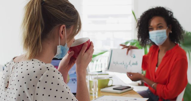 Businesswomen Discussing Financial Report in Office While Wearing Masks - Download Free Stock Images Pikwizard.com