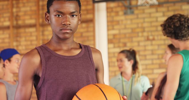 Portrait of high school boy standing with basketball in the court