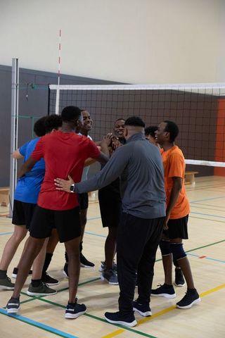 African american male volleyball team huddling on indoor court for unity, energy, teamwork