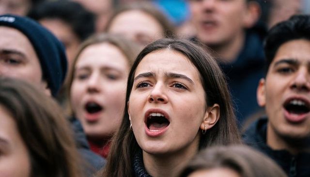 Young woman chanting passionately in protest crowd during winter rally close-up portrait
