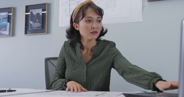 Biracial businesswoman sitting at table and inspecting schema alone at office - Download Free Stock Photos Pikwizard.com