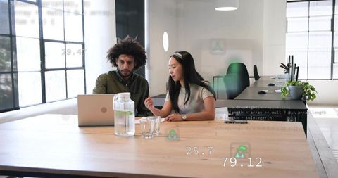 Collaborating colleagues reviewing code on laptop in modern open-plan coworking office