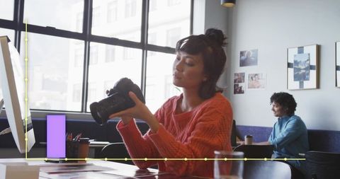 Creative woman inspecting dslr camera at modern shared workspace