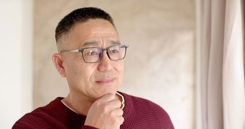 Senior man reflecting near window in cozy home setting