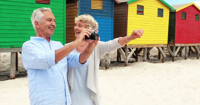 Senior Couple Taking Selfie on Beach with Colorful Beach Huts - Download Free Stock Images Pikwizard.com