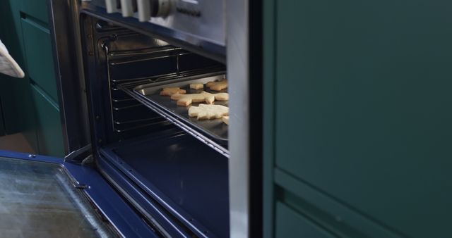 Close-up view of freshly baked holiday cookies shaped like stars inside an oven. Ideal for use in holiday-themed blogs, food and recipe websites, or promotional material for cooking appliances and baking supplies. Celebrates the joy of homemade holiday treats during festive season.