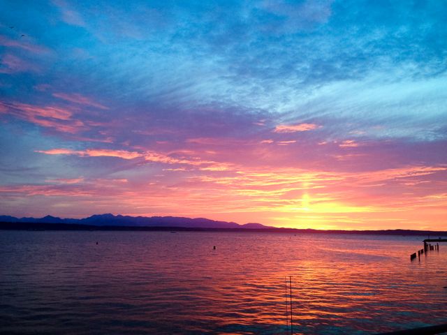 Stunning Sunset Over Calm Sea with Mountains in Background and Piers - Download Free Stock Photos Pikwizard.com