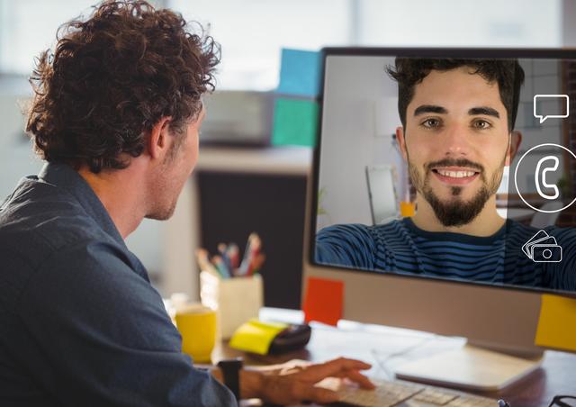 Man engaged in a video call on a computer screen in an office environment. Ideal for illustrating remote work, virtual meetings, digital communication, and modern office settings. Useful for articles or advertisements related to business communication, technology in the workplace, and professional interactions.