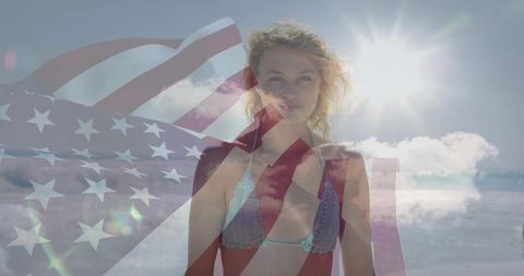 Young woman at beach with american flag overlay feeling freedom
